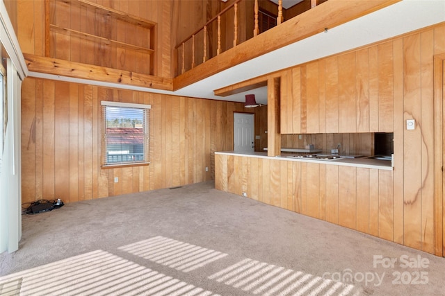 kitchen with carpet flooring, wooden walls, and a high ceiling