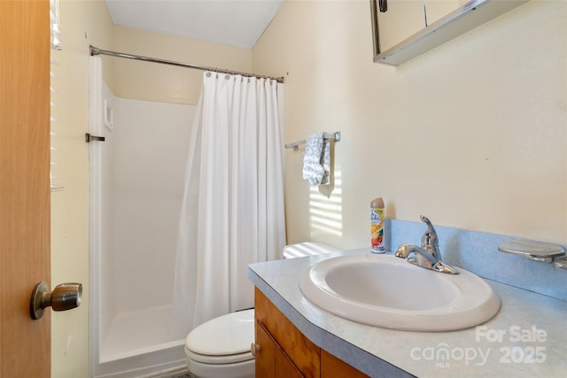 bathroom with toilet, a stall shower, and vanity