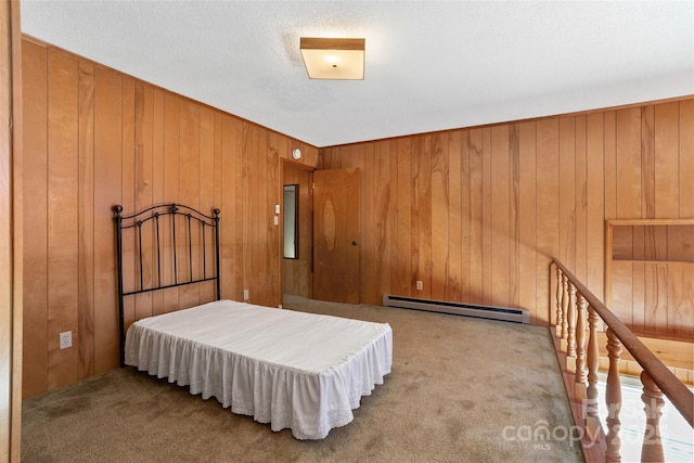 bedroom with a baseboard heating unit, wooden walls, and light colored carpet