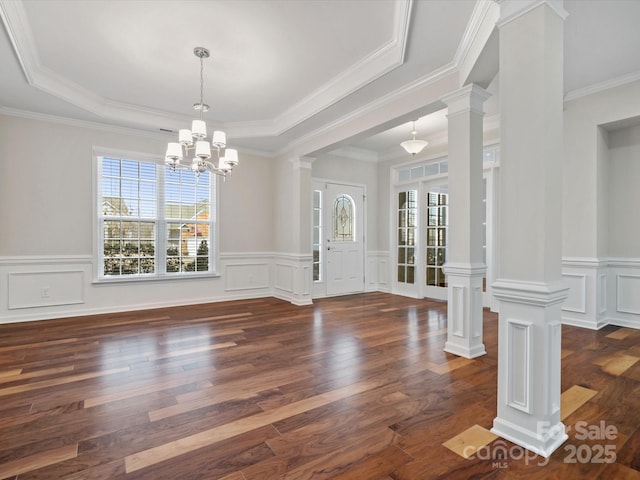 entryway featuring decorative columns, hardwood / wood-style flooring, a wainscoted wall, an inviting chandelier, and a tray ceiling