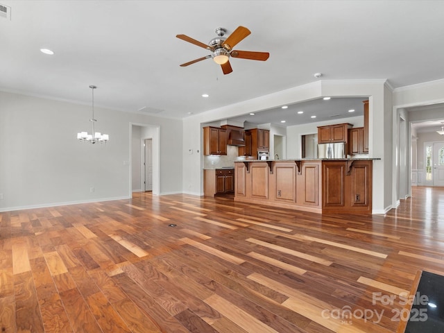 unfurnished living room with baseboards, visible vents, ornamental molding, wood finished floors, and ceiling fan with notable chandelier