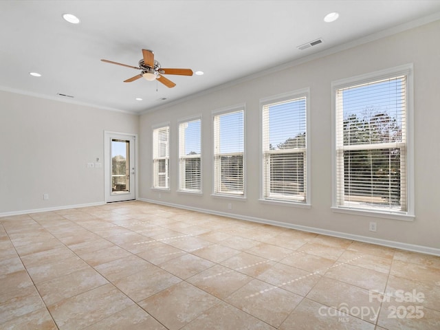 empty room with a wealth of natural light, baseboards, visible vents, and crown molding