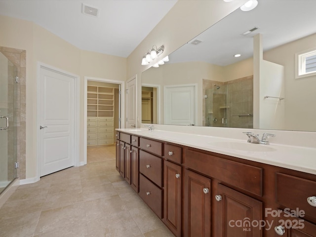 full bath featuring a stall shower, a spacious closet, visible vents, and a sink