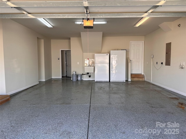 garage with a garage door opener, a sink, freestanding refrigerator, and electric panel