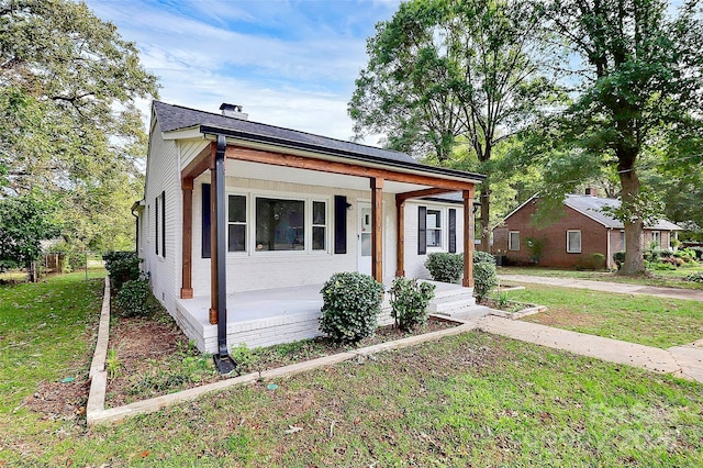 bungalow with a front yard, covered porch, and brick siding