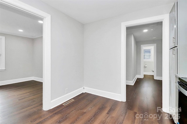 hallway featuring visible vents, baseboards, and wood finished floors