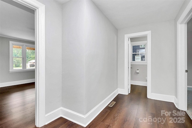 corridor featuring wood finished floors, visible vents, and baseboards