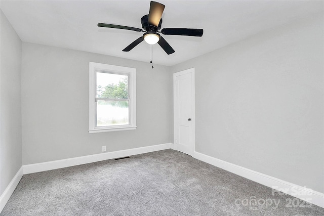 carpeted spare room featuring a ceiling fan, visible vents, and baseboards