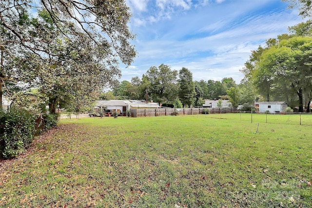 view of yard featuring a storage unit, fence, and an outbuilding