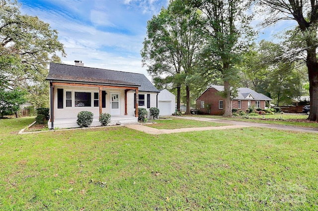 view of front of home with driveway, a garage, a chimney, an outbuilding, and a front lawn