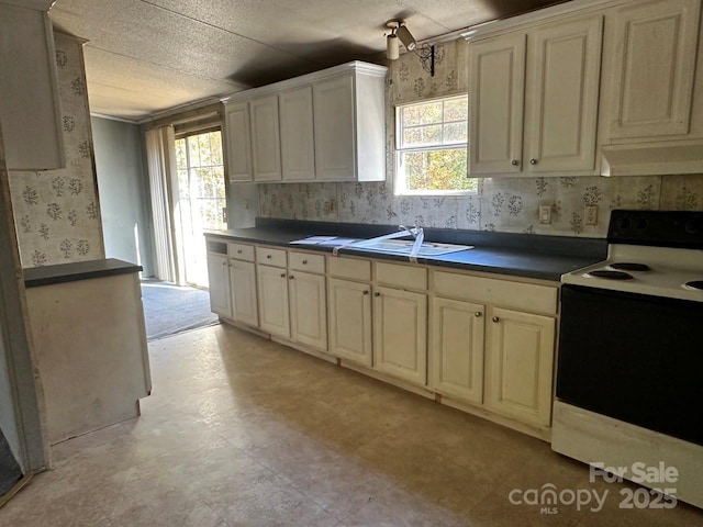 kitchen with under cabinet range hood, a sink, electric range oven, dark countertops, and wallpapered walls