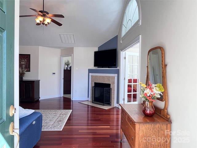 living room with baseboards, ceiling fan, wood finished floors, a fireplace, and a wealth of natural light