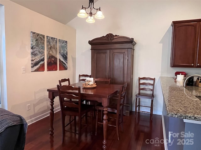 dining room featuring dark wood-style floors, baseboards, and an inviting chandelier