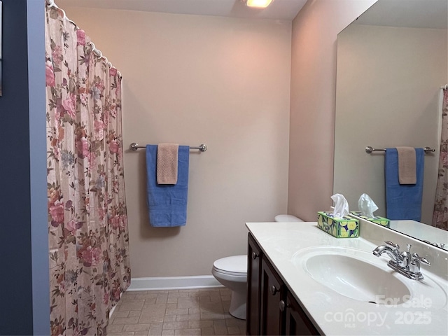 bathroom with curtained shower, vanity, toilet, and baseboards