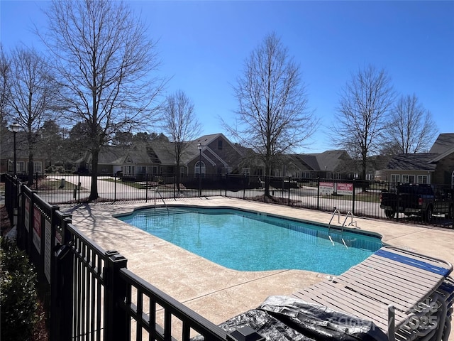 pool with a patio, fence, and a residential view