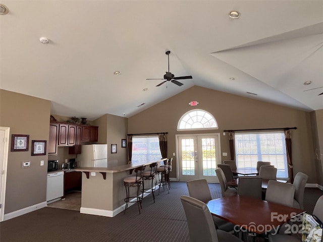 kitchen featuring white appliances, open floor plan, light countertops, and a kitchen breakfast bar