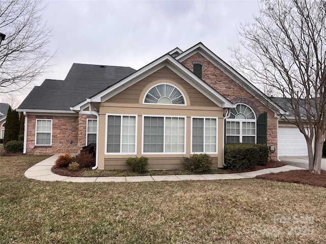 view of front facade featuring a garage, stone siding, a front lawn, and roof with shingles