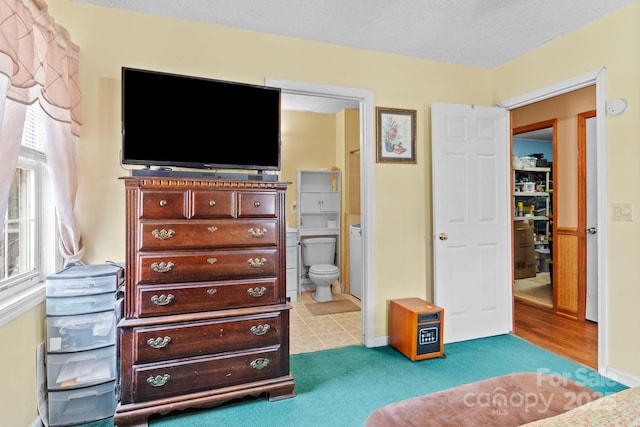 carpeted bedroom with a textured ceiling, baseboards, and ensuite bathroom