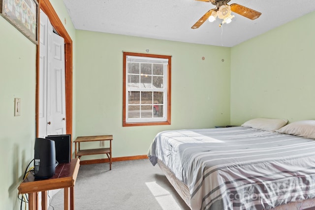 bedroom featuring light carpet, a ceiling fan, baseboards, and a textured ceiling