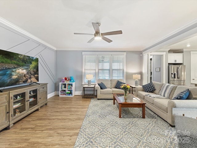 living area featuring light wood-style floors, baseboards, a ceiling fan, and crown molding