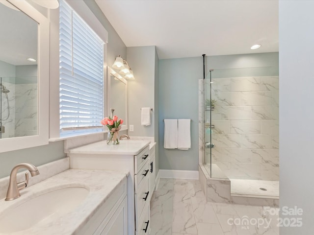 bathroom featuring a marble finish shower, baseboards, a sink, marble finish floor, and two vanities