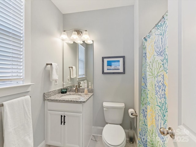 full bathroom with a wealth of natural light, vanity, toilet, and baseboards