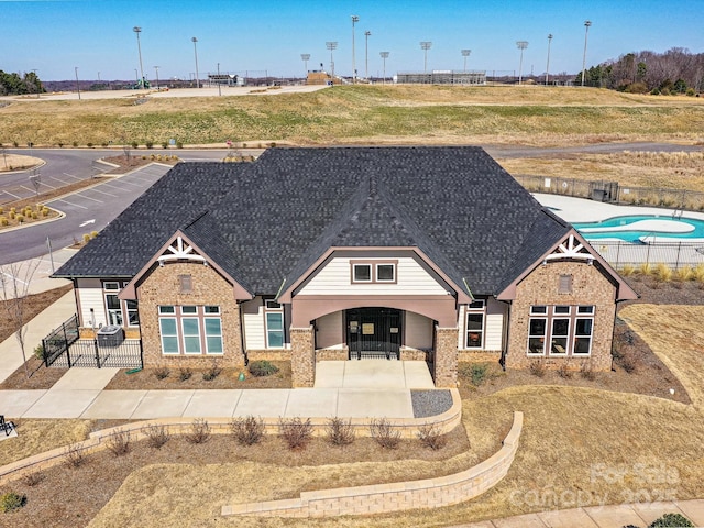 view of front of house with a shingled roof, fence, and brick siding