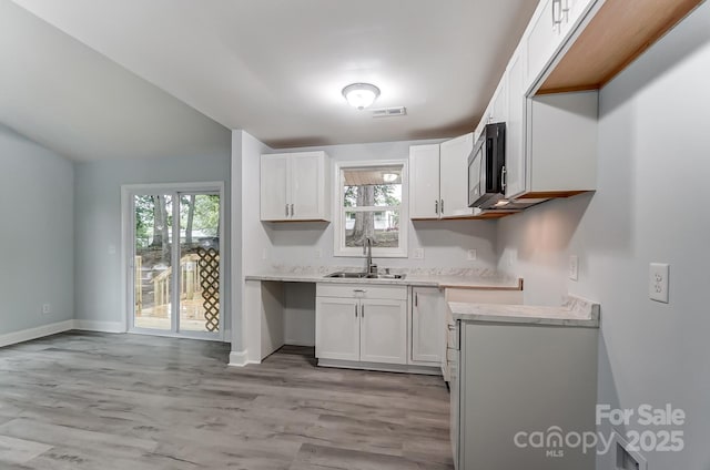 kitchen featuring a sink, visible vents, white cabinetry, light countertops, and stainless steel microwave