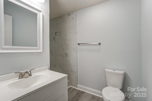 bathroom with toilet, baseboards, wood finished floors, and vanity