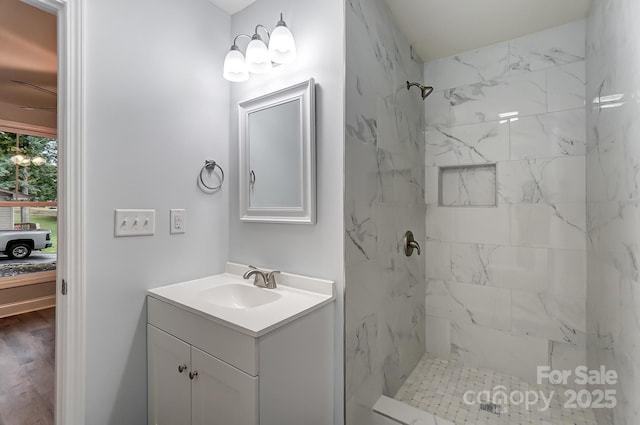 bathroom featuring wood finished floors, vanity, a marble finish shower, and ensuite bathroom