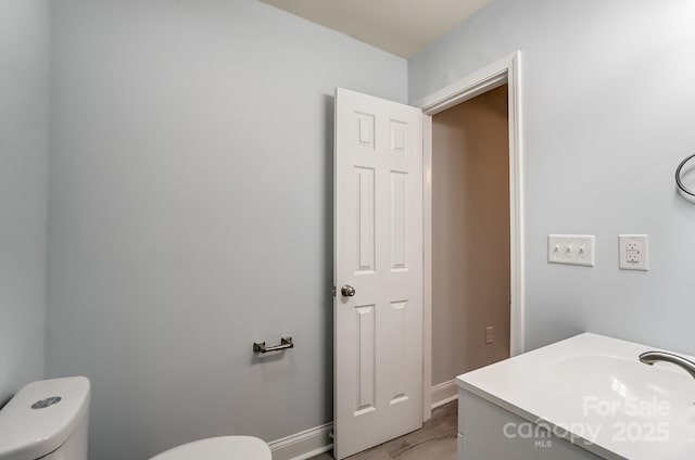 bathroom featuring vanity, toilet, and baseboards