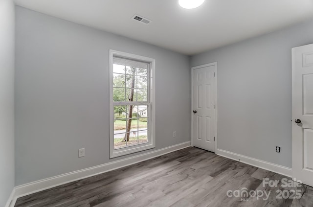 unfurnished room with wood finished floors, visible vents, and baseboards