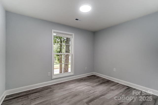 spare room featuring visible vents, baseboards, and wood finished floors