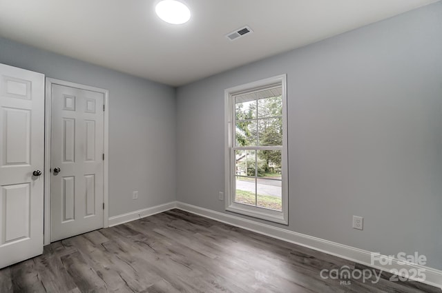 unfurnished room with baseboards, visible vents, and wood finished floors