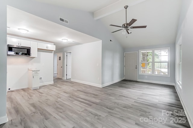 unfurnished living room with light wood-type flooring, beam ceiling, visible vents, and baseboards