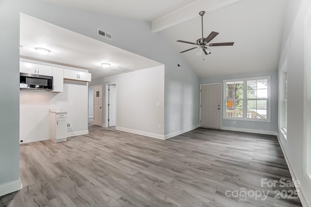 unfurnished living room featuring light wood finished floors, beamed ceiling, visible vents, and baseboards