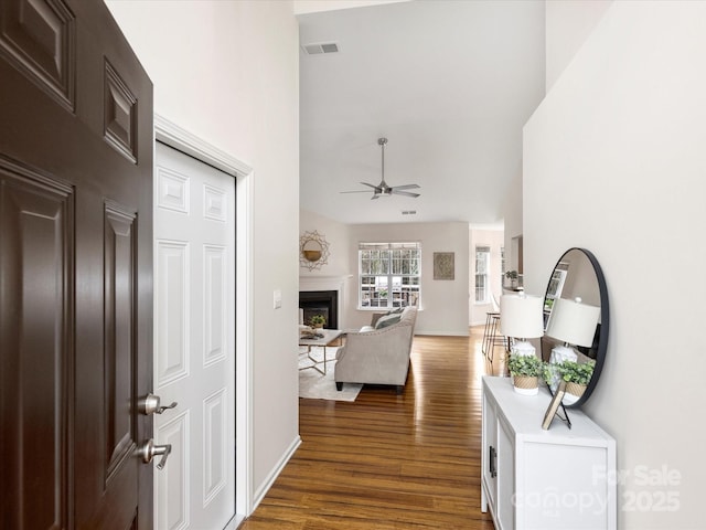 hall with visible vents, wood finished floors, and a towering ceiling