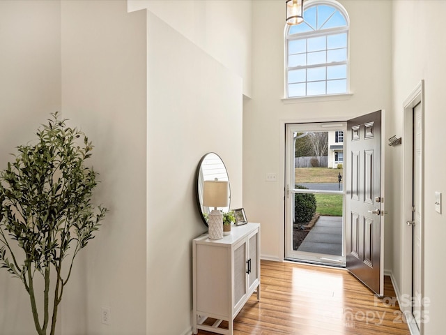 entrance foyer featuring light wood-style floors and a towering ceiling