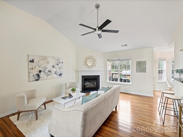 living area featuring visible vents, a healthy amount of sunlight, lofted ceiling, and wood finished floors