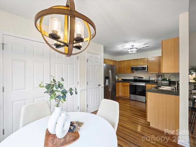 kitchen with a sink, dark countertops, dark wood finished floors, and stainless steel appliances