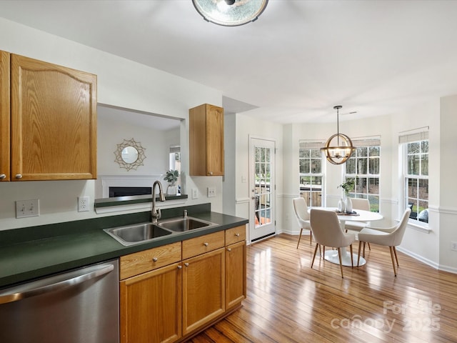 kitchen featuring hardwood / wood-style floors, a sink, dishwasher, dark countertops, and a notable chandelier