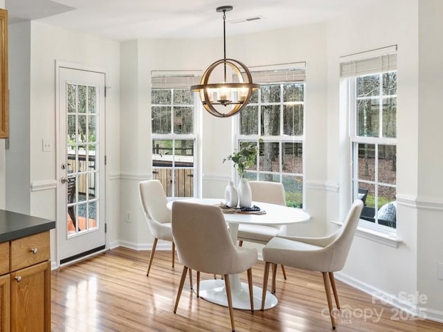 dining space featuring a notable chandelier, wood finished floors, visible vents, and baseboards