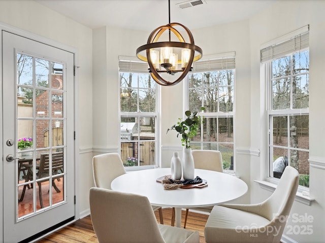 dining area with a notable chandelier, wood finished floors, and visible vents