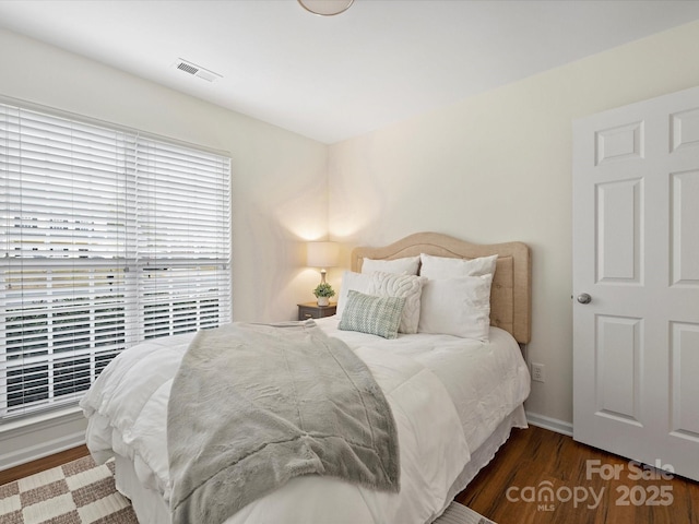 bedroom with visible vents, baseboards, and wood finished floors