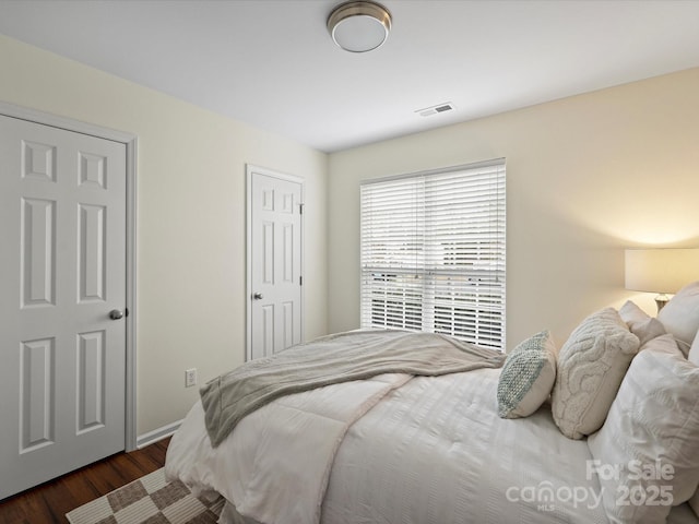 bedroom with dark wood-style floors, visible vents, and baseboards