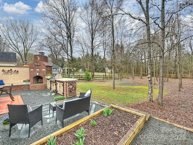 view of yard with a patio, fence, and an outdoor brick fireplace