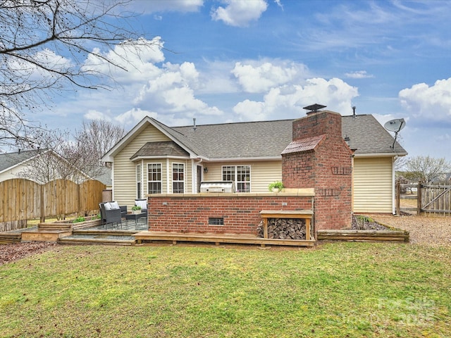 rear view of property featuring a wooden deck, fence private yard, roof with shingles, a lawn, and a chimney