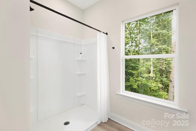 full bathroom with baseboards, wood finished floors, and a shower with curtain