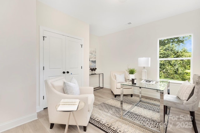 living area featuring light wood finished floors, visible vents, and baseboards