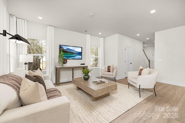 living area featuring visible vents, recessed lighting, light wood finished floors, baseboards, and stairs